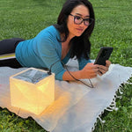Load image into Gallery viewer, Woman charging phone in park using MEGAPUFF solar lantern on warm light