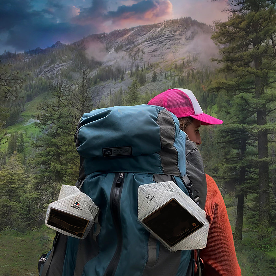 Camper carrying SolarPuff lanterns attached to backpack for off-grid lighting