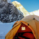 Load image into Gallery viewer, The sun is about to set as the solar lantern. SOLARPUFF is hanging on the out side of this orange tent.The mountains of Everest are looming behind the small orange tent. The solar lantern SolarPuff has been charging all day as it hangs out side the tent.solar-camping -lantern-perfect for any adventure- so-light-and flat-packs. No -batteries-needed. Solarpuff
