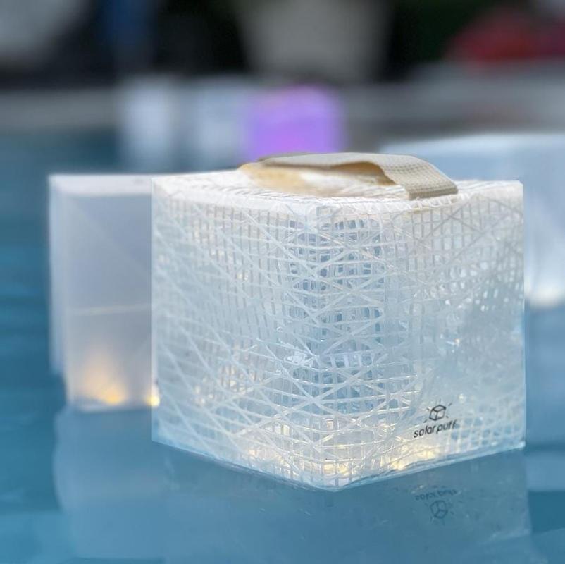 Multiple SolarPuff waterproof lanterns floating in pool at night