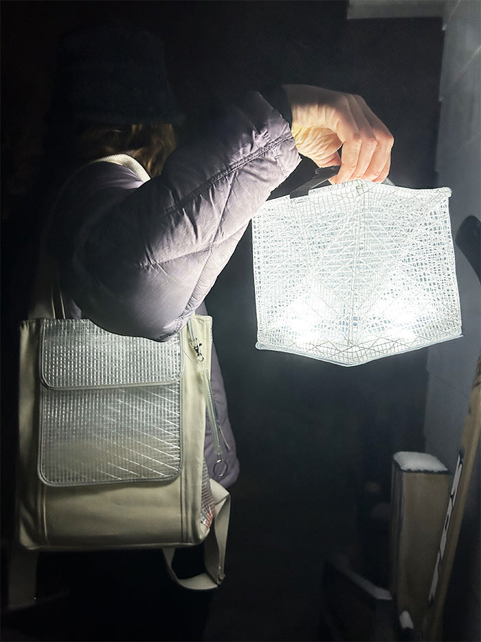 Person holding lantern outside, brightening the dark night.