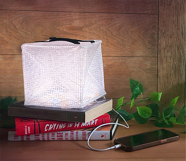 MegaPuff solar lantern sitting on a book charging a phone.