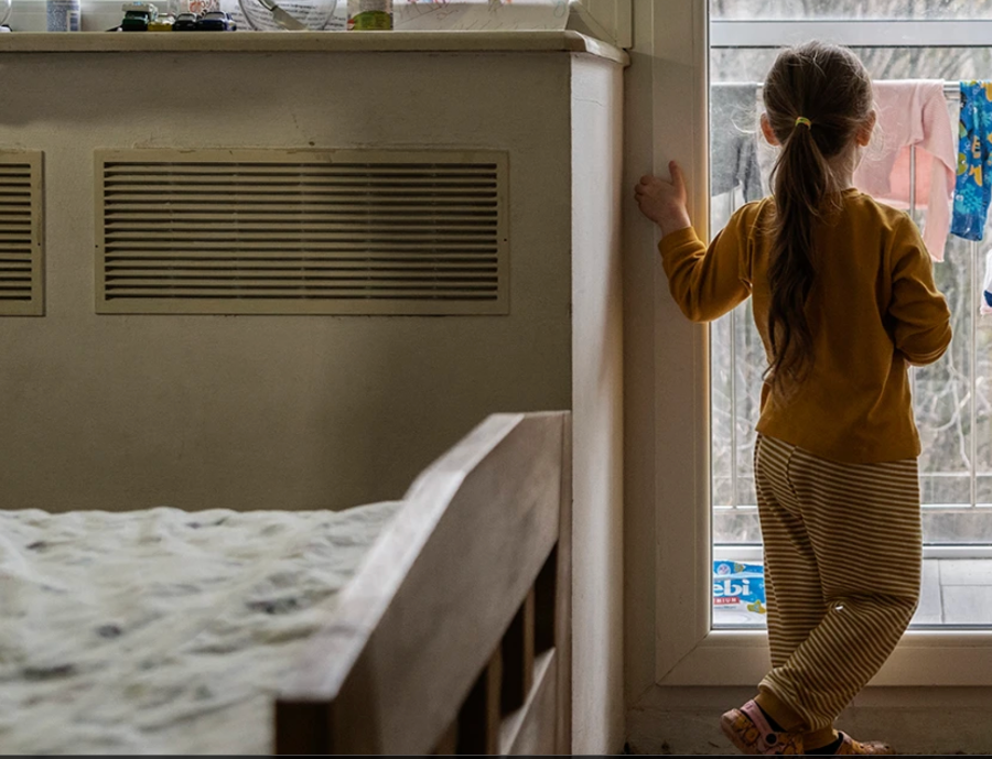 Solar Lights for Children in Ukraine. Child looks out window at Lviv Children's Hospital for pediatric cancer care. Children have migrated to the hospital to avoid bombings on frontline.