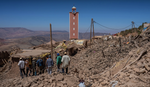 Load image into Gallery viewer, People standing on rubble after earthquake.
