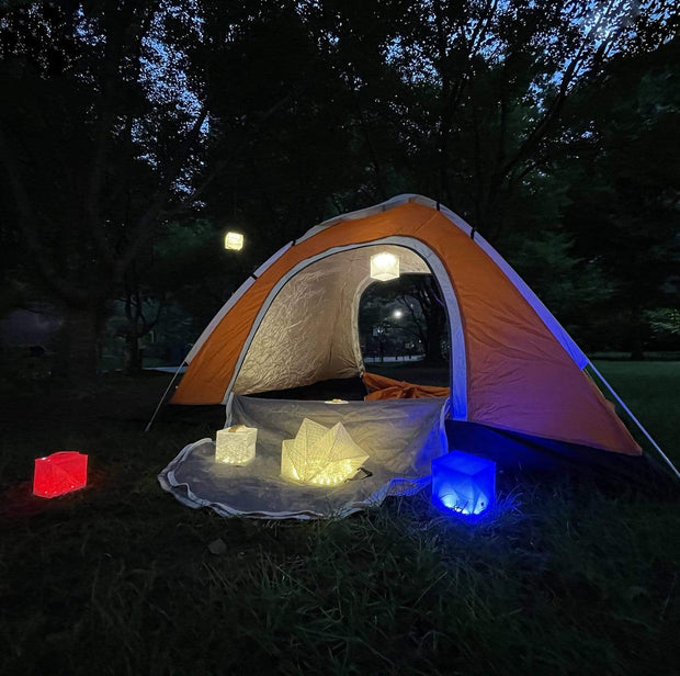 Camping lantern that's eco-friendly and flat packs for easy travel. Enjoy your evening event, shown here lighting a group of kids hanging out by the sunset with our modern cube of light. 
