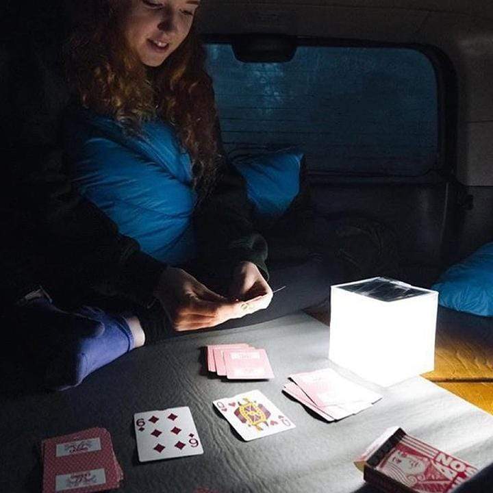 Helix Hybrid lantern in bright mode lighting car camping while person plays cards