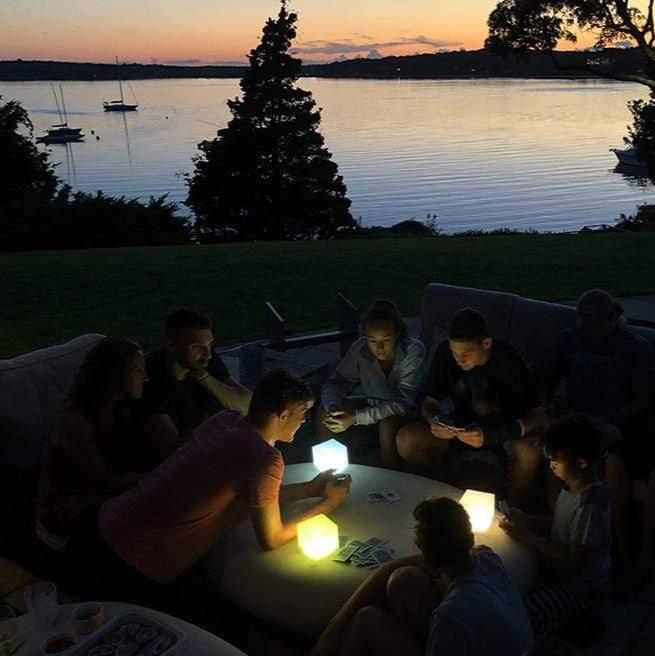 Group of friends using Helix Hybrid solar lanterns on patio at dusk for outdoor gathering