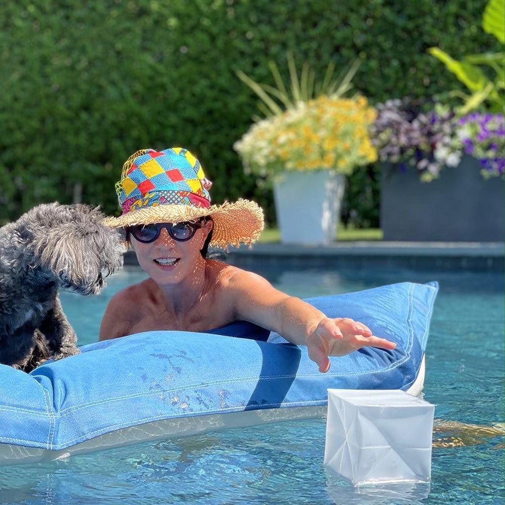 Woman reaching for Helix Hybrid lantern in pool, outdoor waterproof use