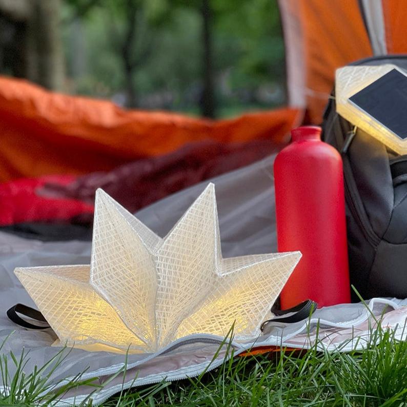 QWNN solar lantern near tent, with water bottle and SolarPuff lantern in background